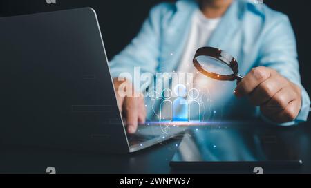 HRM, human manage, Businessman use magnifying glass to find human icon for business CRM or Customer Relation Management and customer focus target grou Stock Photo