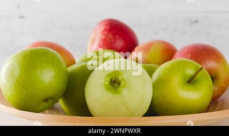 Red and green apples on a wooden plate close-up Stock Photo