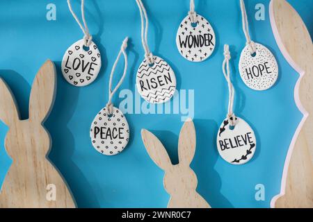 Group of wooden bunny ears and clay Easter eggs with words RISEN HOPE BELIEVE PEACE LOVE WONDER White air dry clay for making decor to EASTER holiday. Creating hobby recreation activity that involves fingers. DIY crafting Modern art  Stock Photo