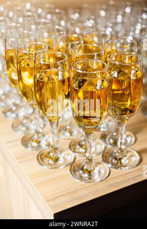 Rows of sparkling apple cider filled glasses on a wooden counter, ready for a festive celebration or toast. Stock Photo