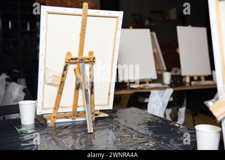 An art studio scene featuring easels with blank canvases, paint brushes, and a creative atmosphere ready for an art class. Stock Photo
