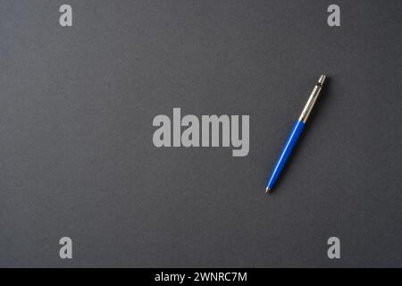 Blue plastic and metal ballpoint pen on dark gray background Stock Photo