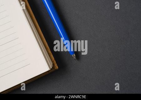 Ballpoint pen made of blue plastic and metal standing on lined notebook Stock Photo
