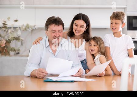 Happy father looking through papers together with his family Stock Photo