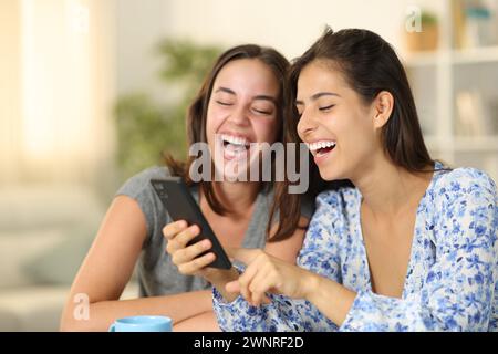 Funny friends laughing checking phone at home Stock Photo