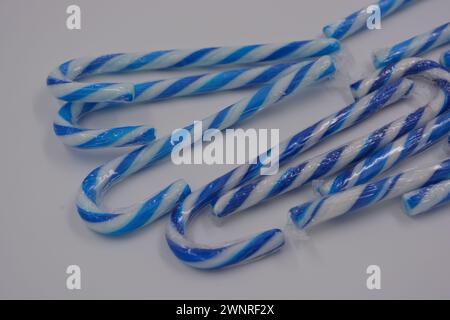 Happiness, joy, sweets, New Year candies, Christmas white lollipops with blue stripe arranged on white background. Stock Photo