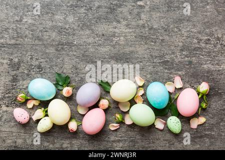 Happy Easter. Easter eggs on colored table with yellow roses. Natural dyed colorful eggs background top view with copy space. Stock Photo