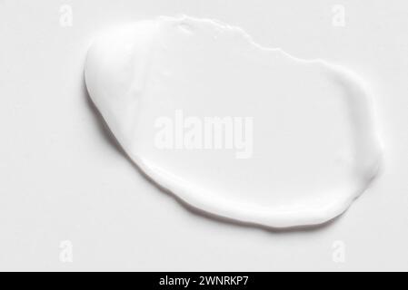 White cosmetic cream lotion swatch smear smudge on white background. Stroke of light gel cosmetic product. Stock Photo