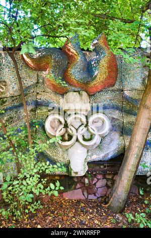 Hidden behind overgrowth is a mosaic tile olympic flame, torch symbol