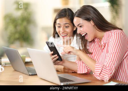 Happy tele workers watching amazing phone content on smart phone at home Stock Photo