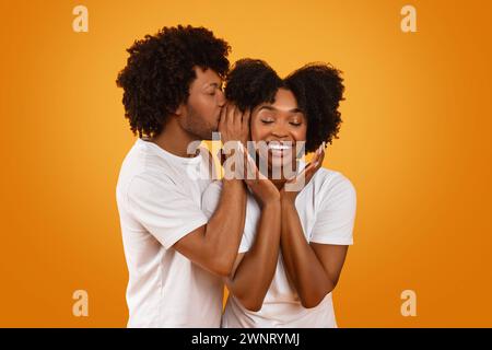 Black guy whispering something on his girlfriend ear Stock Photo