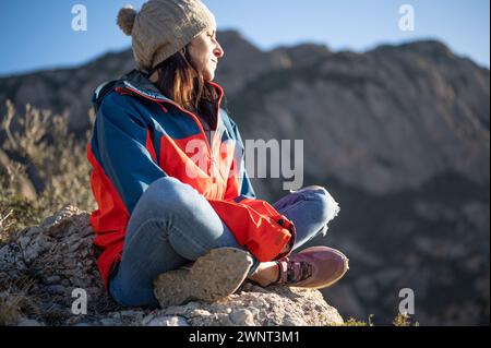 Woman sitting on a rock looking out over the landscape. Stock Photo