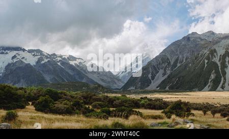 Cloudy sky, green mountains, dry grasses, path and trees. A rural ...