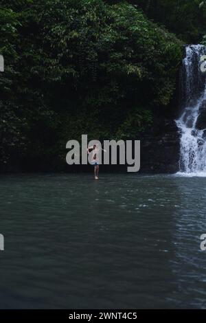 Man jumps from a cliff into the Alin-Alin waterfall. Bali Stock Photo