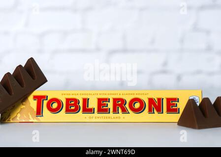 Closeup of bars of Toblerone chocolate swiss milk chocolate with honey and almond nougat on a white table. Illustrative editorial Stock Photo