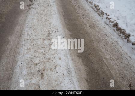 Snowdrifts on the side of the road. Bad weather and traffic. Snow on asphalt. Difficult driving conditions. Winter slush on the road. Wet weather Stock Photo