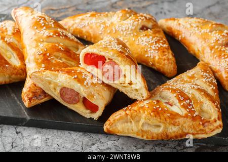 Puff pastry turnover with sausage, cheese and pepper close-up on a marble board on the table. Horizontal Stock Photo