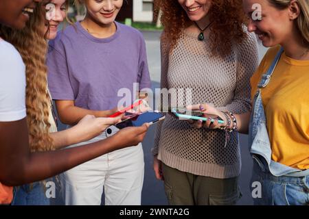 Young women using smartphones. Female friends standing in a circle on the street with modern devices Stock Photo