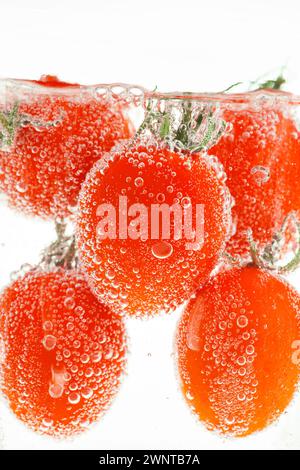 Fresh tomatoes submerged in water with bubbles clinging to the skin Stock Photo