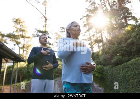 Senior biracial woman and man practice yoga outdoors at sunrise at home Stock Photo