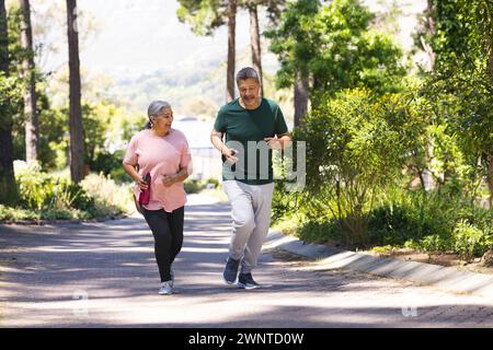 Senior biracial woman and biracial man jogging together in a park Stock Photo