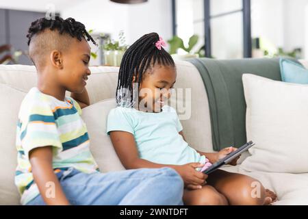 African American sister with braided hair and a brother with a mohawk are using a tablet Stock Photo