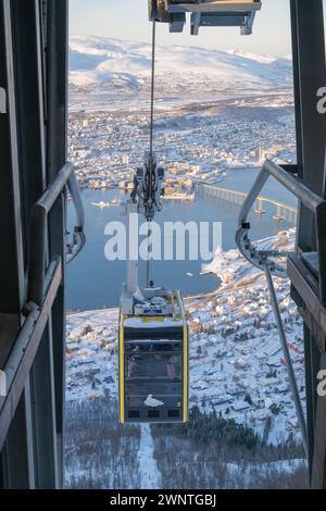 View from cable car station above Tromso looking back down the mountain towards the city with the cable car approaching into the station, Stock Photo