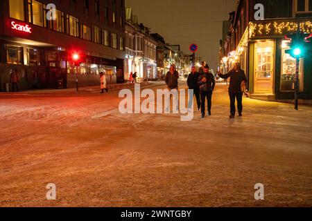 Group of friends crosses the street on a night out in Tromso, Norway, in the cold of winter with snow covered street and side walk Stock Photo