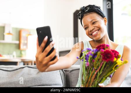 Young African American woman takes a selfie with a bouquet of colorful flowers with copy space Stock Photo