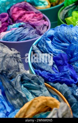 Bright colourful traditional silk shawls or scarves on a market counter, abstract multicolour background Stock Photo