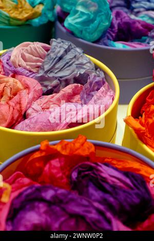 Bright colourful traditional silk shawls or scarves on a market counter, abstract multicolour background Stock Photo