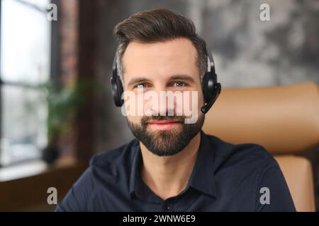 Caucasian handsome and cheerful young businessman wearing a headset looking at the camera, male customer support worker  Stock Photo