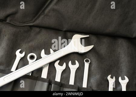 Set of wrenches in different sizes in black tools back. One wrench lying across the others. Stock Photo