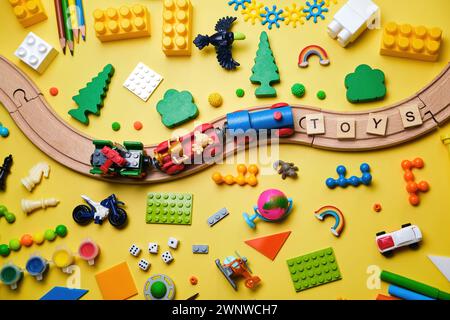 Banner with Set of different children's toys, wooden railroad, train, constructor on a yellow background with copy space for text. Top view, flat lay. Stock Photo