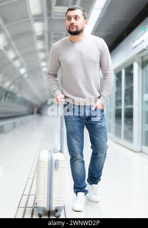 Young man walking through metro station with suitcase Stock Photo