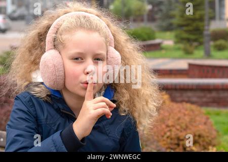 Gloomy child. The upset kid hands closes ears. The concept the little girl doesn't agree, the child doesn't want to listen. unwillingness to listen, B Stock Photo