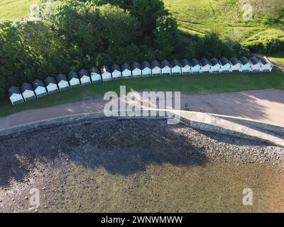 An aerial drone photograph of a row of white beach huts close to a sandy beach by the sea at Goodrington Sands near Paignton Devon. Stock Photo