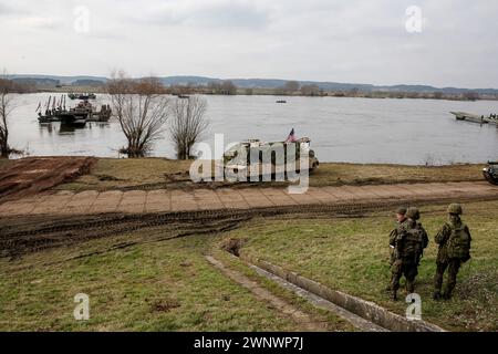 Korzeniewo, Poland on March 4, 2024. NATO soldiersexercise ability to cross armored vehicles through Vistula river on ferries during NATO's  Dragon-24 exercise, a part of large scale Steadfast Defender-24 exercise. The Steadfast Defender-2 exercises, which will take place mainly in Central Europe, will involve some 90,000 troops from all NATO countries as well as Sweden. Their aim is to deter and present defensive abilities in the face of aggression. Stock Photo