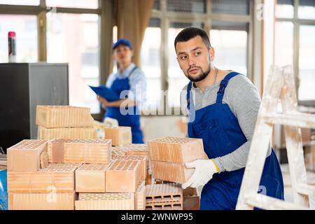 Builder carrying bricks while working in apartment Stock Photo