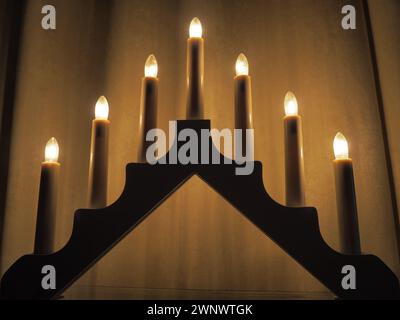 Schwibbogen arch luminaire in the form of a triangular candlestick. Yellow background. Evening, romantic, festive, religious or mystical atmosphere Stock Photo