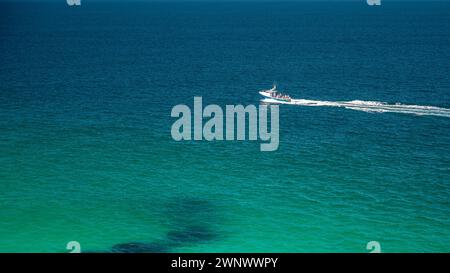 A single motorboat, cutting through the clear seas, just off the coast of St. Ives, Cornwall, England on a sunny summer's day. Room for copy Stock Photo