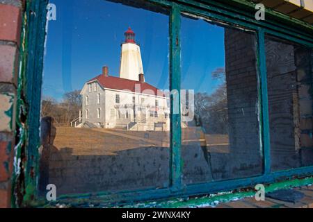 The Sandy Hook Lighthouse reflected on the partially cracked window pane of a Fort Hancock structure -91 Stock Photo