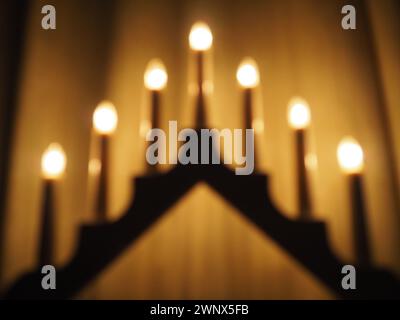 Schwibbogen arch luminaire in the form of a triangular candlestick. Yellow background. Romantic, festive, religious or mystical atmosphere. Burning Stock Photo