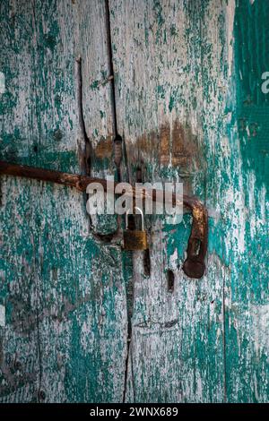 old rusty weather beaten weathered shabby chic gate lack or lock on a green painted distressed doorway. Stock Photo