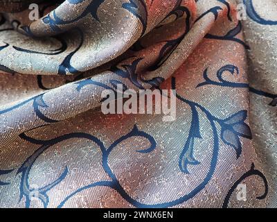 silk blue fabric with golden curls. Textiles for upholstery, curtains and festive clothing. The fabric is softly folded in waves. Stock Photo