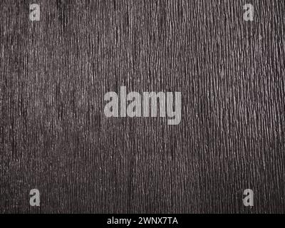 Black or gray corrugated paper. Uneven surface. Abstract monochrome background. Wavy edges of the paper sheet. Lighting gradient. Corrugated texture Stock Photo