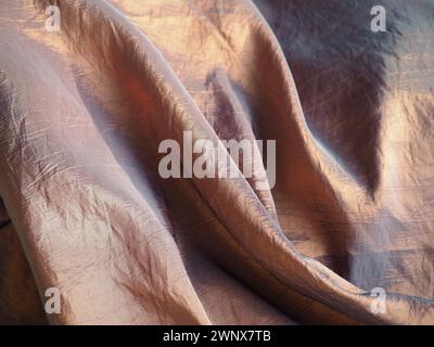 Beautiful fabric - taffeta, gently folded in waves. Crumpled material that looks like silk or brocade. Overflow and color gradient at different Stock Photo