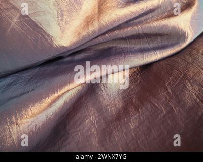 Beautiful fabric - taffeta, gently folded in waves. Crumpled material that looks like silk or brocade. Overflow and color gradient at different Stock Photo