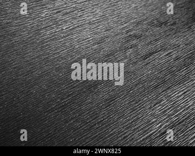 Black or gray corrugated paper. Uneven surface. Abstract monochrome background. Wavy edges of the paper sheet. Lighting gradient. Corrugated texture Stock Photo