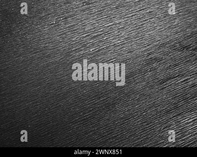 Black or gray corrugated paper. Uneven surface. Abstract monochrome background. Wavy edges of the paper sheet. Lighting gradient. Corrugated texture Stock Photo